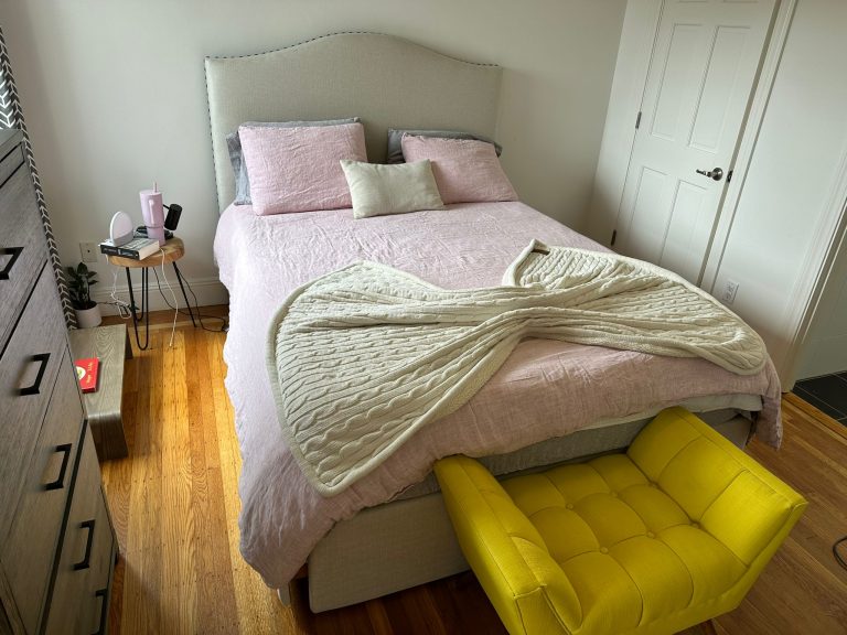 Bedroom with neatly made bed and polished hardwood floors